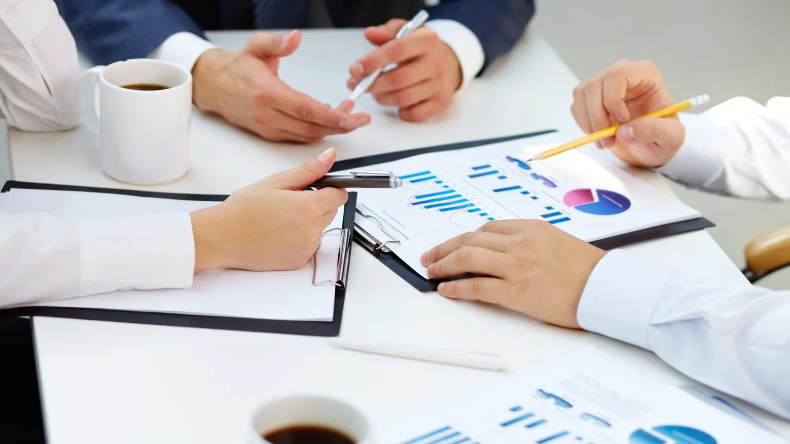 Colleagues at a table going over printed bar and pie charts
