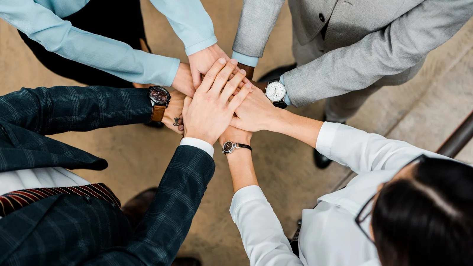 Five colleagues stacking their hands together, seen from above